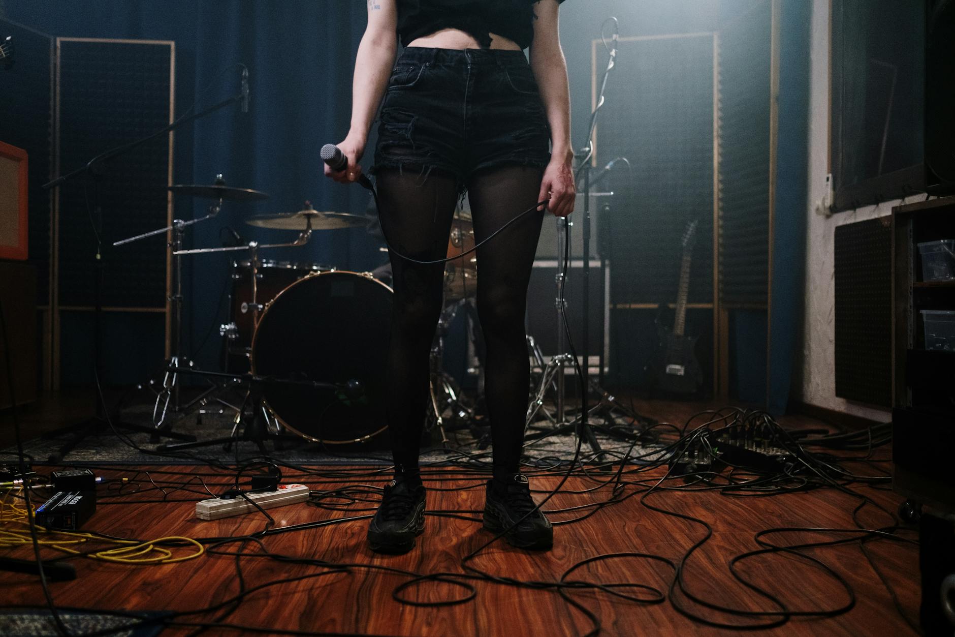 woman in black denim shorts standing on brown wooden floor